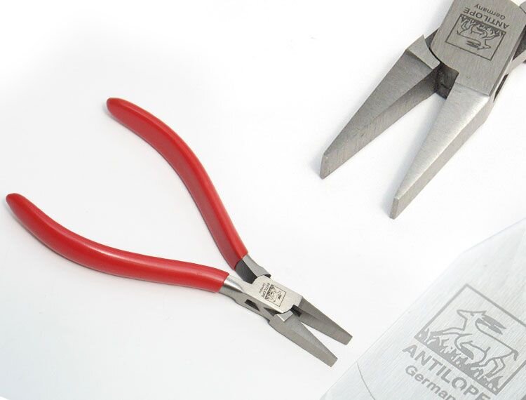 Zdjęcie przedstawia kleszcze płaskie oraz zbliżenie na ich część z płaskimi szczękami. Kleszcze składają się z dwóch rękojeści obciągniętych osłoną PCV i szczypców. Szczypce kleszczy są rozwarte i posiadają płaskie szczęki.