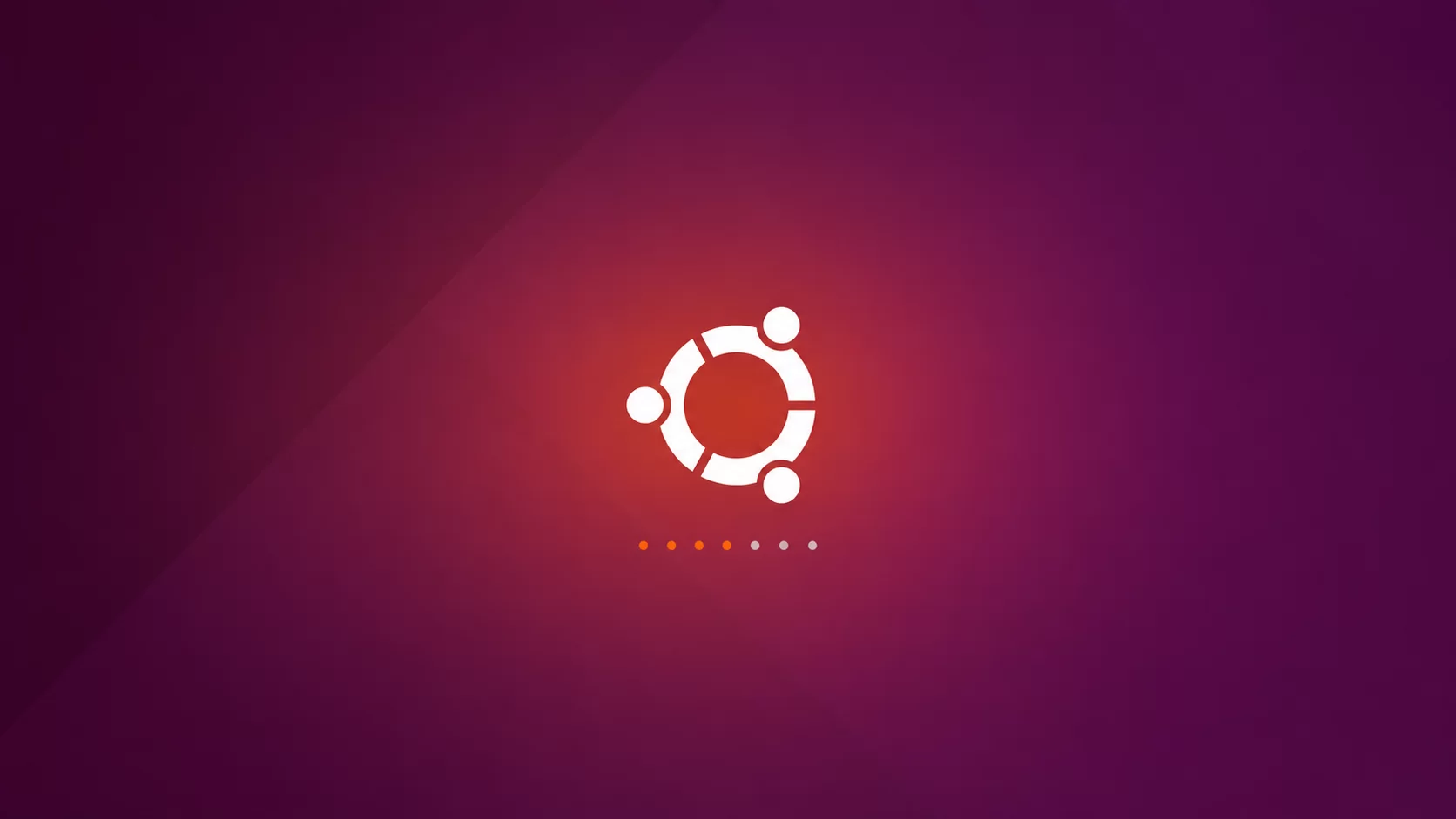 Na zdjęciu pokazano ekran powitalny dla systemy: Ubuntu. W centralnej części ekrany na czerwonym tle znajduje się symbol w kształcie białego okręgu z wpisanym w środku okręgiem zbudowanym z trzech identycznych niepołączonych ze sobą łuków. Nad każdym z łuków w połowie jego długości znajduje się kropka.Pod napisem narysowanych jest pięć równomiernie rozmieszczonych kropek. 